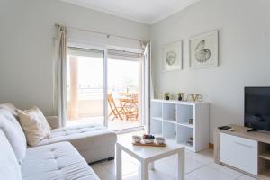 een witte woonkamer met een bank en een tv bij Quinta da Barracuda by Golden Zenith in Albufeira