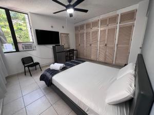 una camera da letto con un letto e una TV a schermo piatto di Habitación céntrica y espaciosa con A/A a Città di Panama Altre 19 foto