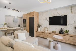 a living room with a couch and a tv on a wall at Infinity luxury suite in Malia
