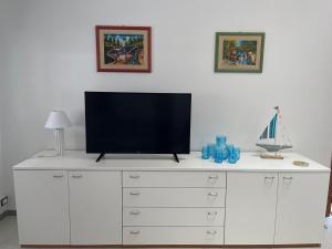 a television on top of a white dresser at Villa Baia del Silenzio in Agnone Bagni