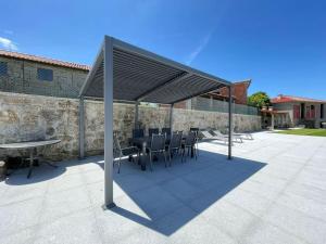 patio con tavolo e sedie sotto un baldacchino di Casa Curto a Terras de Bouro