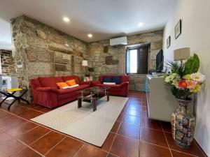 un soggiorno con divani rossi e un muro in pietra di Casa Curto a Terras de Bouro