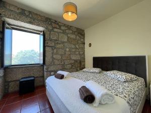 una camera da letto con un letto e un muro di pietra di Casa Curto a Terras de Bouro Altre 17 foto