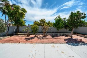 two trees on a brick sidewalk next to a fence at Mins to Disney Chic 3BR with Arcade in Santa Ana