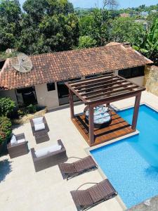 a swimming pool with chairs and a gazebo at Casa Amaral 3 in São Pedro da Aldeia