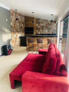 a living room with a red couch and a bar at Casa Amaral 3 in São Pedro da Aldeia