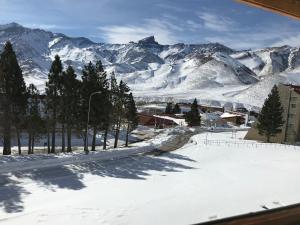a snow covered mountain range with a town in the foreground at LAS LEÑAS - ATENAS - 5 Personas in Las Lenas