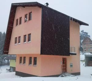 a building with a black roof in the snow at Apartments Gaga in Jahorina