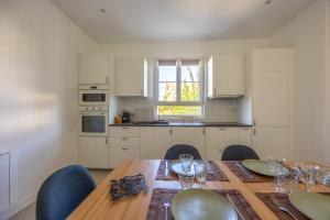 a kitchen with a wooden table with chairs and a dining room at La Maison du Fleuve - Welkeys in Dives-sur-Mer