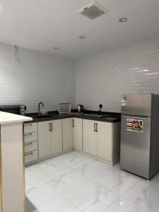 a kitchen with white cabinets and a stainless steel refrigerator at رُقيّ للشقق الفندقية rogy VIP in Taif +2 photos
