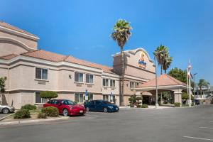 a hotel with two cars parked in a parking lot at Comfort Suites in Tulare
