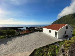 een wit huis met een rood dak op een heuvel bij Longitude 31 House in Faja Grande