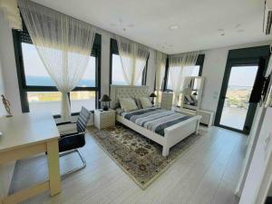 a bedroom with a bed and a desk and windows at Exquisite Sunset Penthouse in Haifa