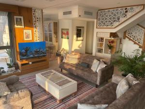 a large living room with couches and a tv at Exquisite Sunset Penthouse in Haifa