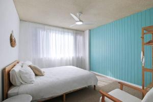 a bedroom with a bed and a blue wall at Suttons Beach Sunrise in Redcliffe