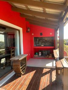 a porch with a red wall and a bench on a deck at Casa MAAT Villa Serrana in Villa Serrana