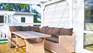 eine Terrasse mit einem Sofa und einem Tisch auf einer Veranda in der Unterkunft Delta Mare - Ferienhaus Folklore - 250m zum Strand in Dziwnów