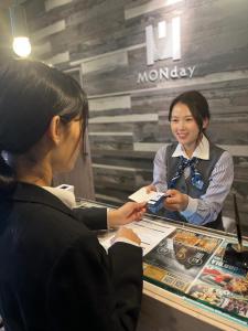 東京的住宿－hotel MONday Haneda Airport，站在柜台与女人谈话的女人