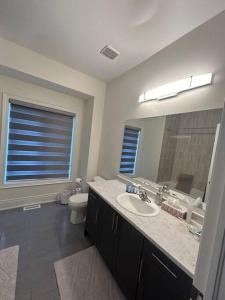 ein Badezimmer mit Waschbecken, Toilette und Spiegel in der Unterkunft Luxury, Home Away from Home in Brampton
