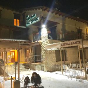 un bâtiment avec un panneau indiquant un restaurant dans la neige dans l'établissement Apart-Hotel Selva Nevada, à La Virgen de la Vega