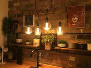 a kitchen with lights hanging from a brick wall at The Coachmans Cottage in Rock Ferry