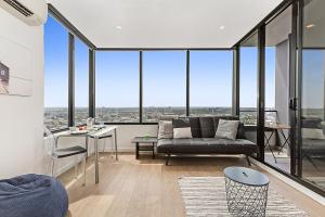 salon z kanapą i oknami w obiekcie Sunshine CBD Apt with Stunning Views plus Pool w Melbourne