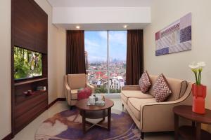 a living room with a couch and chairs and a large window at Somerset Kencana Jakarta in Jakarta