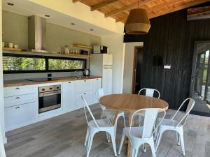 Una cocina con una mesa de madera y sillas blancas. en Casa Nera Chica, en Chapadmalal