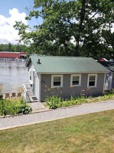 a small house sitting next to a body of water at Lakefront Cottage on Beautiful Lake Winnipesaukee in Laconia