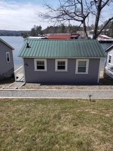 a purple house with a green roof next to the water at Lakefront Cottage on Beautiful Lake Winnipesaukee in Laconia