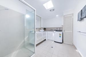 bagno bianco con doccia e frigorifero di Blue Lagoon Airlie Beach ad Airlie Beach