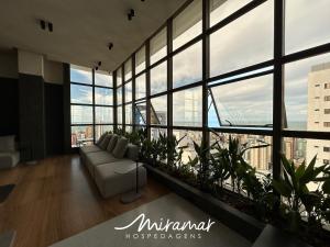 a living room with a couch and large windows at Co-House Tambaú in Tambaú