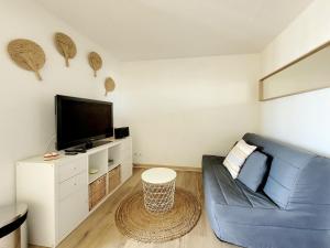 Una sala de estar con un sofá azul y un televisor de pantalla plana. en Canet-en-Roussillon T2 Moderne - Parking - Clim - 2ème étage avec ascenseur - 4 pers - FR-1-794-136, en Canet-en-Roussillon