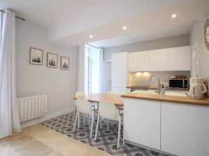 a kitchen with white cabinets and a table and chairs at Bel Apt T3 rénové avec terrasse et wifi, centre La Bourboule, proche thermes, max 5 pers - FR-1-608-270 in La Bourboule