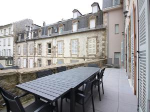 a black table and chairs on a balcony with buildings at Bel Apt T3 rénové avec terrasse et wifi, centre La Bourboule, proche thermes, max 5 pers - FR-1-608-270 in La Bourboule
