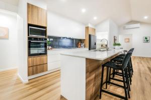 a kitchen with a counter and two stools at Aquatic Abode in Agnes Water