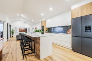 a kitchen with white cabinets and a bar with stools at Aquatic Abode in Agnes Water