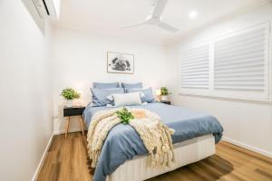 a bedroom with a bed with blue sheets and a window at Aquatic Abode in Agnes Water
