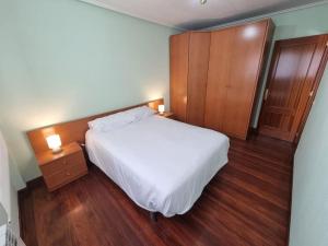 a bedroom with a white bed and a wooden cabinet at Apartamento con piscina privada No mascotas in Medina de Pomar