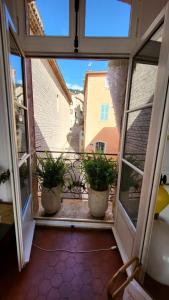 una ventana abierta con 2 macetas en el balcón en Chambre d Hôtes de charme, Coeur de la vieille Ville, en Hyères