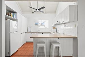 a kitchen with white cabinets and a ceiling fan at Mysa Anglesea Sleeps 7 WiFi SmartTV Cafes Shops in Anglesea