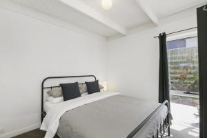 a white bedroom with a bed and a window at Mysa Anglesea Sleeps 7 WiFi SmartTV Cafes Shops in Anglesea