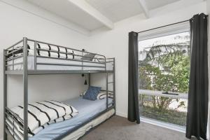a bedroom with two bunk beds and a window at Mysa Anglesea Sleeps 7 WiFi SmartTV Cafes Shops in Anglesea