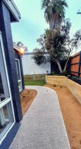 a driveway leading to a house with a palm tree at Mysa Anglesea Sleeps 7 WiFi SmartTV Cafes Shops in Anglesea