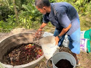 a man standing next to a bucket of dirt at Cookies Salad Resort in Salad Beach