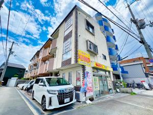 ein weißes Auto, das vor einem Gebäude geparkt ist in der Unterkunft 大阪民泊ー和の家 in Osaka