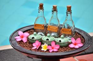 a tray with three wine bottles and some flowers at Pool Villa Merumatta Senggigi in Senggigi