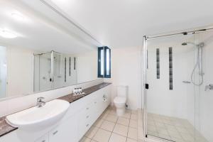 a white bathroom with a sink and a shower at Oaks Sunshine Coast Seaforth Resort in Alexandra Headland