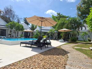 - une terrasse avec 2 chaises et un parasol à côté de la piscine dans l'établissement Thiptara Resort, à Nathon Bay