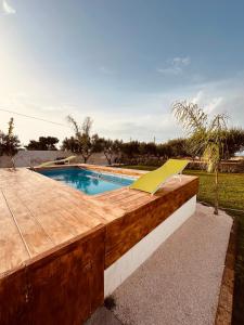 a swimming pool with a wooden deck and a yellow slide at Villa Santo Stefano in Monopoli